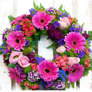 Σύνθεση λουλουδιών σε ειδική βάση με κόκκινα λουλούδια. Ζέρμπερες, γαρύφαλλο και τριαντάφυλλα αποτελούν αυτό το στεφάνι.