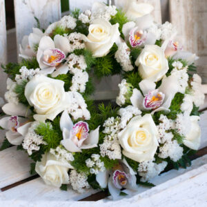 Στεφάνι από λευκά λουλούδια εποχής, σε ειδική βάση από σφουγγάρι. Τριαντάφυλλα, ορχιδέες, και λίγη πρασινάδα.