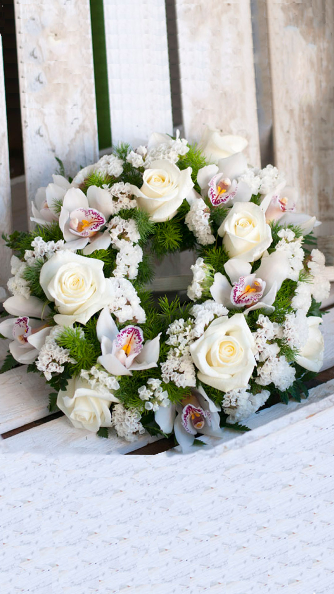 Στεφάνι από λευκά λουλούδια εποχής, σε ειδική βάση από σφουγγάρι. Τριαντάφυλλα, ορχιδέες, και λίγη πρασινάδα.