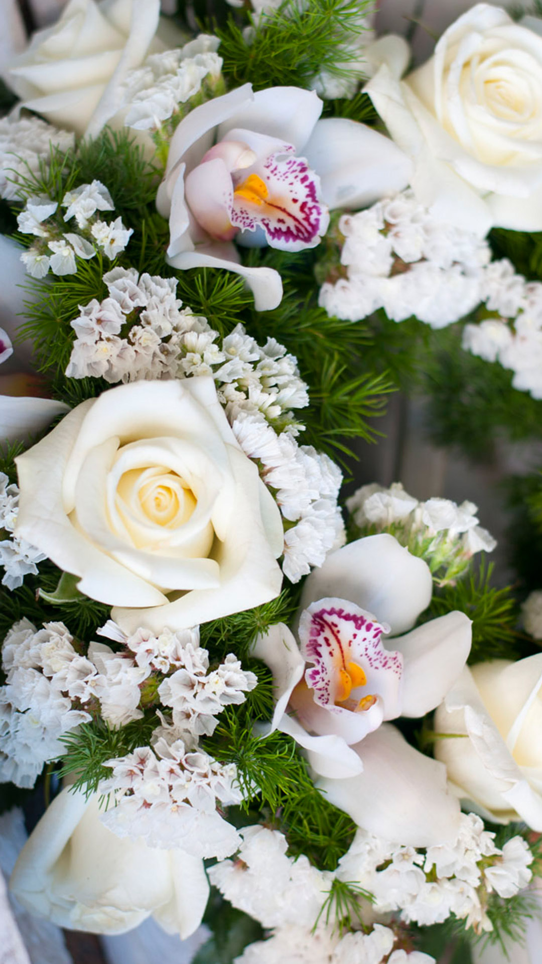 Στεφάνι από λευκά λουλούδια εποχής, σε ειδική βάση από σφουγγάρι. Τριαντάφυλλα, ορχιδέες, και λίγη πρασινάδα.
